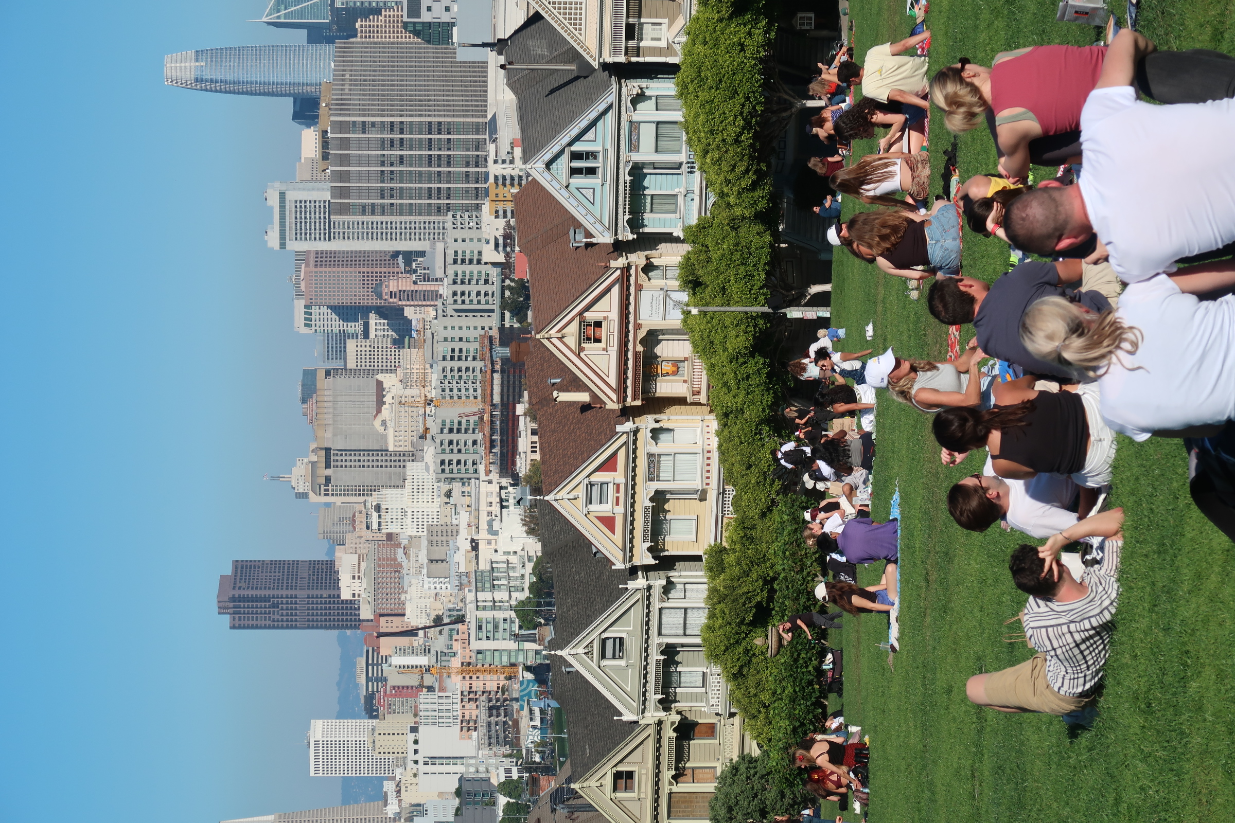 People relaxing in Alamo Square with San Francisco in the background