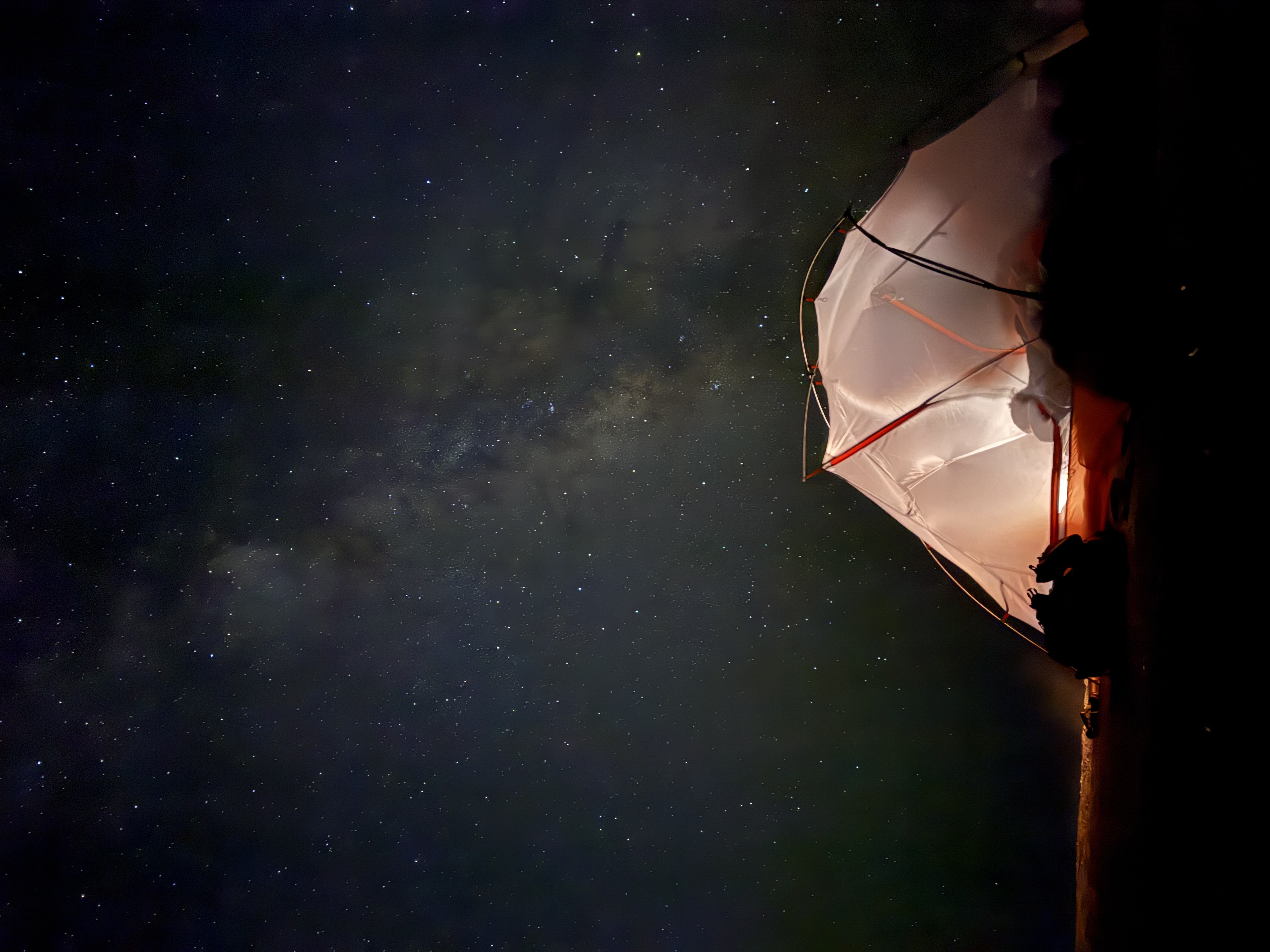 A glowing tent beneath a starry sky